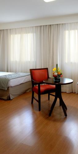 a room with a chair and a table and a bed at Luz Plaza São Paulo in Sao Paulo