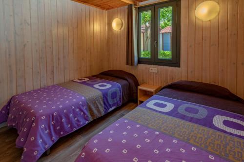 a bedroom with two beds in a wooden cabin at Camping Solmar in Blanes