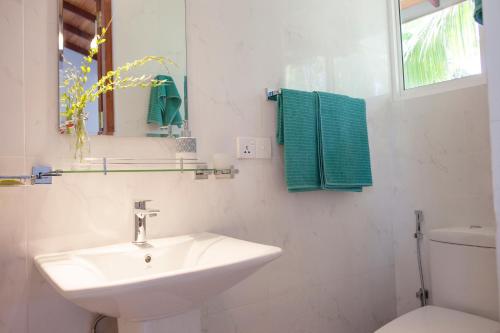 a white bathroom with a sink and a toilet at Alvas house in Hikkaduwa