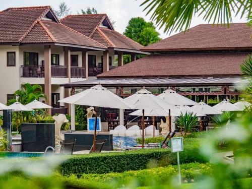a resort with a pool and umbrellas and a person at The Leaf Oceanside by Katathani - SHA Extra Plus in Khao Lak