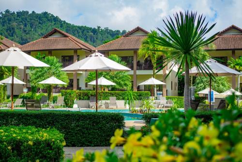 a resort with a pool and umbrellas and a palm tree at The Leaf Oceanside by Katathani - SHA Extra Plus in Khao Lak