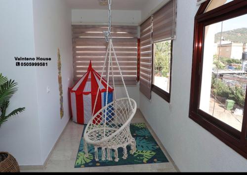 a porch with a swinging chair and a window at valentine House in Deir Ḥannā
