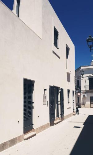 a white building with black doors on a street at meridiano12 in Favignana