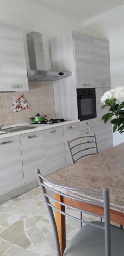 a kitchen with white cabinets and a table with a vase of flowers at Felline House in Manduria