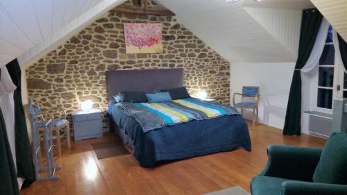 een slaapkamer met een bed en een stenen muur bij Au Pont Ricoul in Saint-Pierre-de-Plesguen