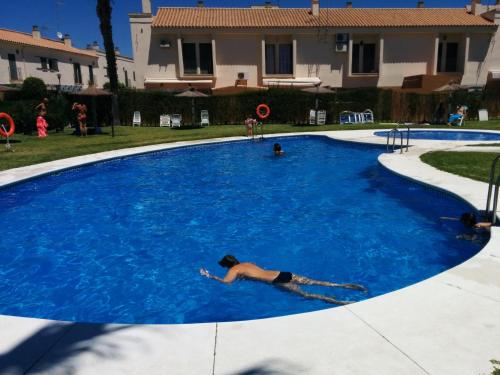 a man laying in a large blue swimming pool at ESTUDIO CON PISCINA Y GARAJE A 100 Mtr DE LA PLAYA in Isla Cristina
