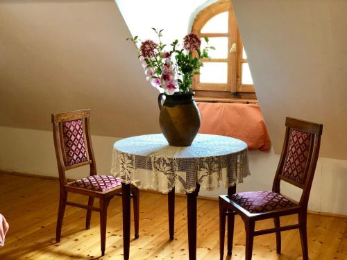 a table with a vase on it with two chairs at The Houses of History - anno 1830 in Tihany