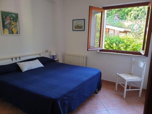a bedroom with a blue bed and a window at Appartamenti Anna in Rio Marina