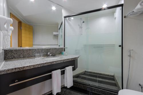 a bathroom with a shower and a sink and a mirror at Golden Tulip Brasília Alvorada in Brasilia