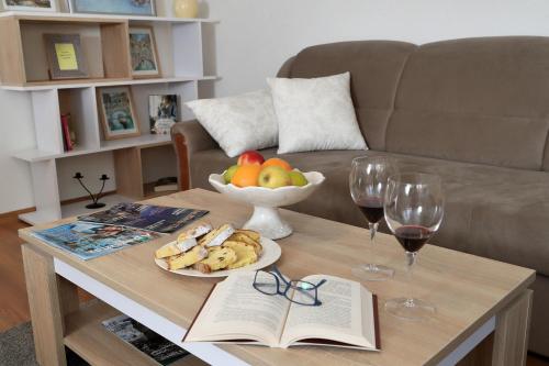 a coffee table with a bowl of fruit and wine glasses at Apartman Sofia in Otočac