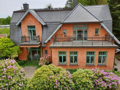 ein großes orangefarbenes Haus mit einem Balkon und Blumen in der Unterkunft Ferienhaus am Wasserturm für 6 Erwachsene und 9 Kinder in Graal-Müritz