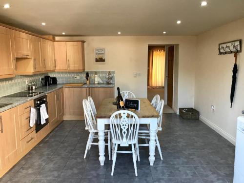 a kitchen with a table and white chairs in it at Westwood Barn Holiday Let in Brough Sowerby