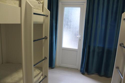 a room with a door and a window with blue curtains at Park Hostel Osh in Osh