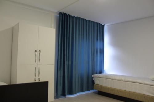a bedroom with a bed and a blue curtain at Park Hostel Osh in Osh