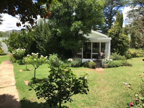 a garden with a house with a lawn and trees at Rosewood Corner, Clarens in Clarens