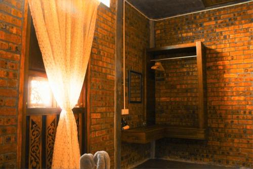 a brick room with a curtain and a window at The Daun Resort Langkawi in Pantai Cenang