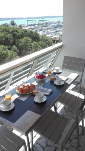 une table avec des assiettes de nourriture au sommet d'un balcon dans l'établissement Grand studio climatisé en bord de mer avec parking sécurisé, au Golfe-Juan