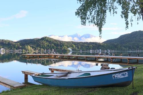 a boat sitting on the grass next to a dock at Strandhotel Orchidee in Sankt Kanzian