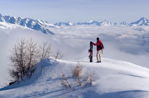 a man standing on top of a mountain with a snowboard at Hotel La Prairie in Crans-Montana