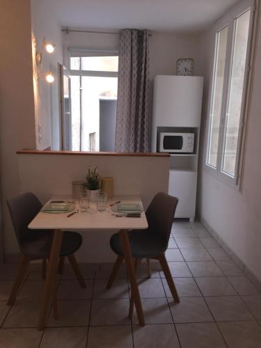 kuchnia ze stołem, krzesłami i kuchenką mikrofalową w obiekcie Studio centre avec terrasse w Awinionie