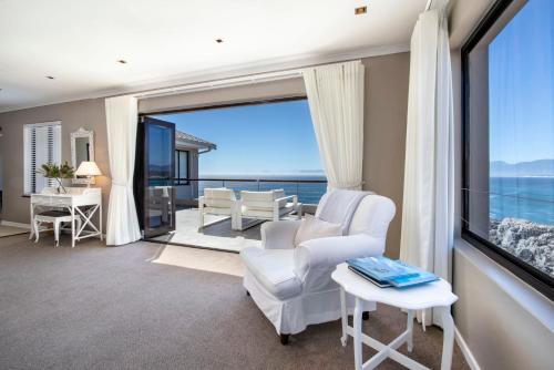 a living room with white chairs and a large window at Cliff Lodge in Gansbaai