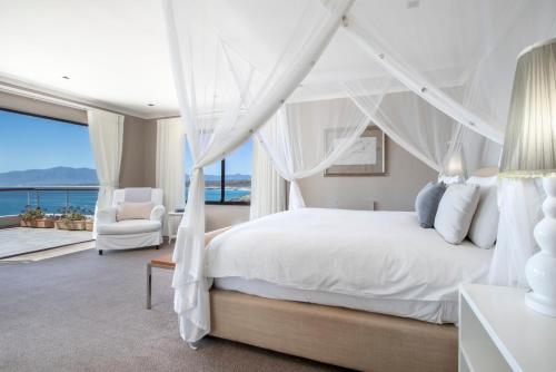 a bedroom with a white bed with a view of the ocean at Cliff Lodge in Gansbaai
