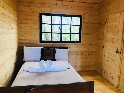 2 toallas blancas en una cama en una habitación de madera en Casa de Arbol, Rancho Tierra Alta en Jarabacoa