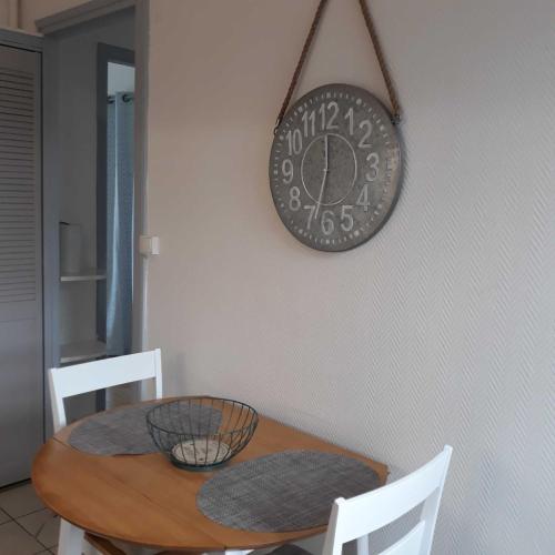 a clock hanging on a wall above a table at L'HORIZON Vue mer et falaises in Fécamp