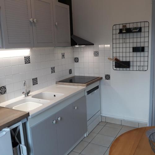 a kitchen with white cabinets and a sink at L'HORIZON Vue mer et falaises in Fécamp
