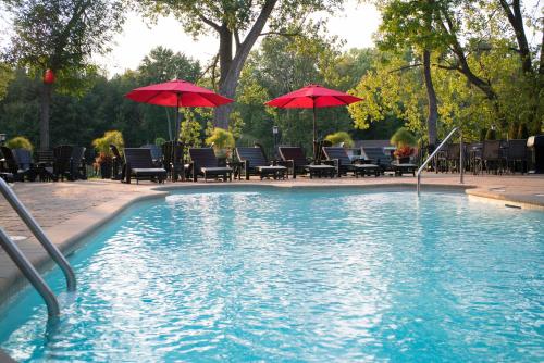 a pool with chairs and umbrellas next to at Hôtel Le Rivage in Rosemère