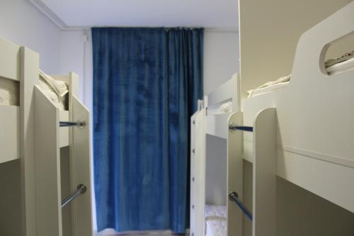 a hospital room with a blue curtain and a window at Park Hostel Osh in Osh