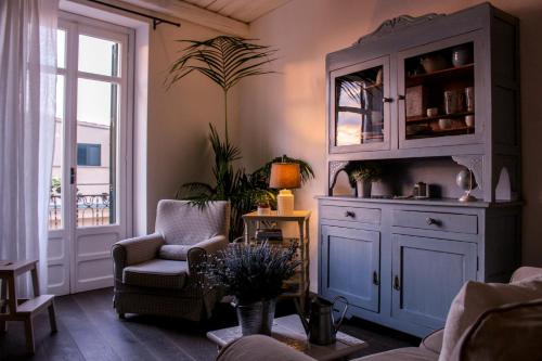 a living room with a cabinet and chairs and a window at Azzurro B&B in Cefalù