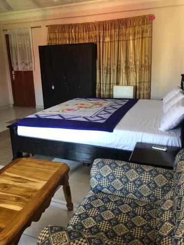 a bedroom with a bed and two chairs and a table at Pemicsa Hotel Accra in Spintex