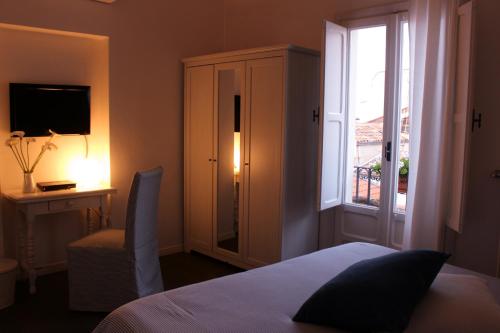 a bedroom with a bed and a window and a television at Azzurro B&B in Cefalù