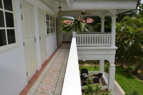 a porch of a white house with a rug at Baan Khun Nang Colonial Residence in Mae Nam