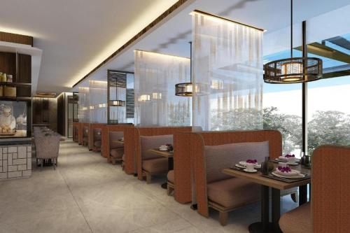 a dining room with chairs and tables and windows at Radisson Lampung Kedaton in Bandar Lampung