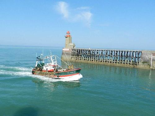 a boat in the water next to a lighthouse at L'HORIZON Vue mer et falaises in Fécamp