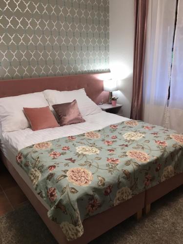 a bedroom with a bed with a floral bedspread at Szent Anna Panzió in Esztergom