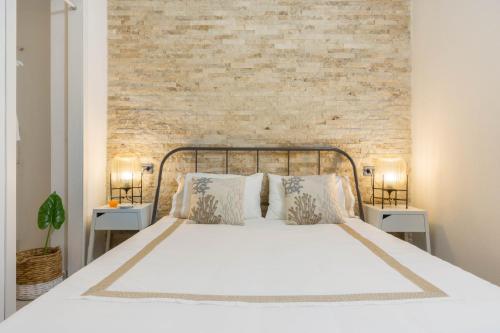 sypialnia z białym łóżkiem z ceglaną ścianą w obiekcie Via San Giacomo 10 w Cagliari