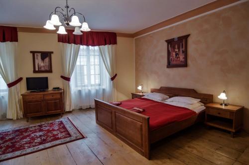 a bedroom with a large bed with a red blanket at Pension Pod Radnicí in Český Krumlov