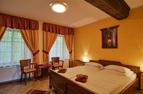 a bedroom with a large bed and chairs and windows at Pension Pod Radnicí in Český Krumlov