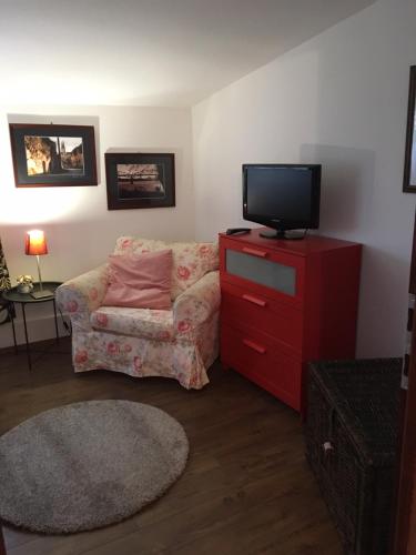 a living room with a couch and a tv on a red dresser at Szent Anna Panzió in Esztergom