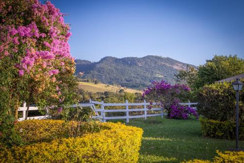 a white fence in front of a field of flowers at Pousada Lua Luana in Cambuquira