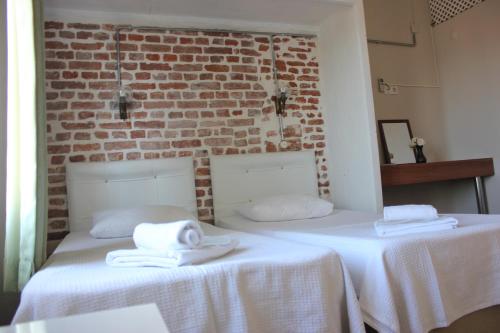 two beds in a room with a brick wall at Macide Hanım Konağı in Ayvalık