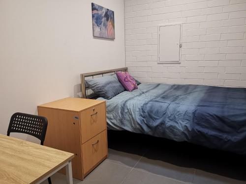 a bedroom with a bed and a dresser and a table at Quokka Backpackers Hostel Perth - note - Valid passport required to check in in Perth