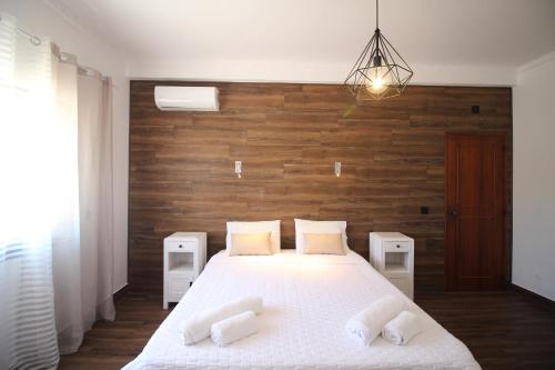 - une chambre avec un lit blanc et un mur en bois dans l'établissement White Bride FZ, à Fuzeta