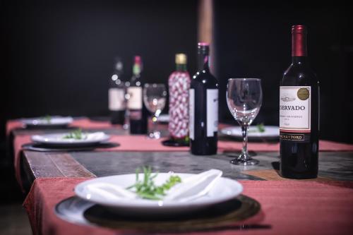 a table with bottles of wine and plates and wine glasses at Pousada Lua Luana in Cambuquira