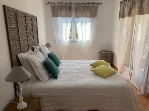 a bedroom with a white bed with green pillows at Villa Pampasgiolu in Tizzano