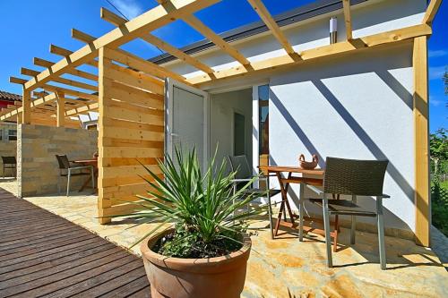 a wooden deck with a table and a pergola at Apartmani Elio in Umag