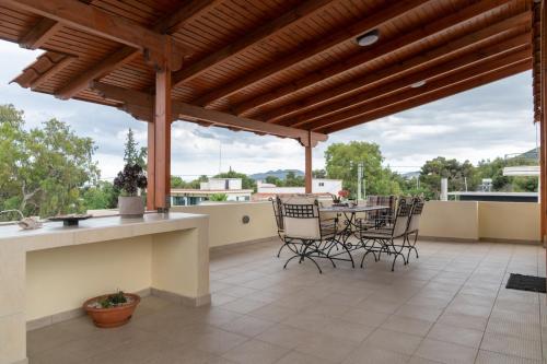a patio with a table and chairs on a roof at Rose's House (Near Airport) in Artemida